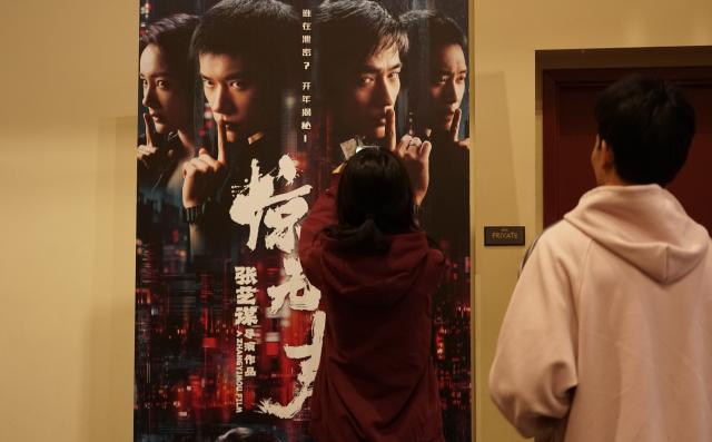 (260218) -- LOS ANGELES, Feb. 18, 2026 (Xinhua) -- Audiences look at a poster of "Scare Out," a contemporary espionage thriller directed by Zhang Yimou, at a cinema in Monterey Park, Los Angeles County, California, the United States, Feb. 17, 2026. Multiple Chinese films are set for release in North America during the period of Chinese New Year, also known as the Spring Festival, including two highly-anticipated blockbusters premiering Tuesday, the Chinese Lunar New Year's Day.
   TO GO WITH "Multiple Chinese blockbusters to hit North American screen during Chinese New Year" (Photo by Zeng Hui/Xinhua)