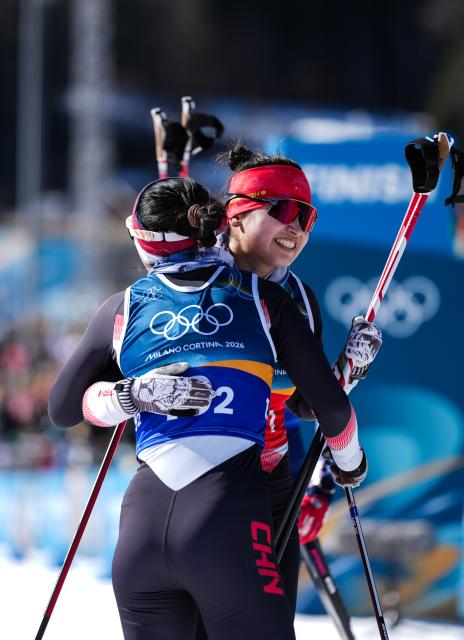 (260218) -- TESERO, Feb. 18, 2026 (Xinhua) -- Dinigeer Yilamujiang (R) of China hugs her teammate Chi Chunxue after the cross-country skiing women's team sprint free final at the Milan-Cortina 2026 Olympic Winter Games in Tesero, Italy, Feb. 18, 2026. (Xinhua/Peng Ziyang)