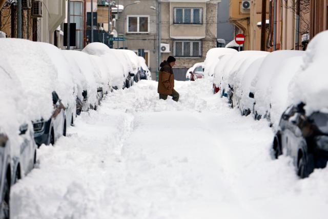 (260218) -- BUCHAREST, Feb. 18, 2026 (Xinhua) -- A man walks on a snow-covered street in Bucharest, Romania, on Feb. 18, 2026. A heavy snowstorm hit southern and southeastern Romania overnight, prompting a red alert in Bucharest and disrupting road, air and maritime traffic, authorities said on Wednesday. (Photo by Cristian Cristel/Xinhua)
