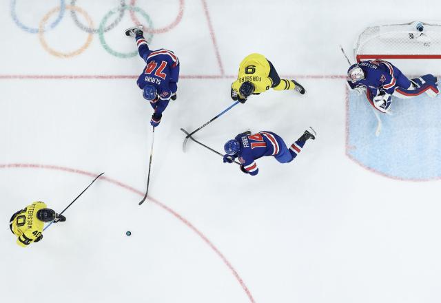 (260219) -- MILAN, Feb. 19, 2026 (Xinhua) -- Players of both teams compete during the ice hockey men's play-offs quarterfinal between Sweden and the United States at the Milan-Cortina 2026 Olympic Winter Games in Milan, Italy, Feb. 18, 2026. (Xinhua/Zhang Haofu)