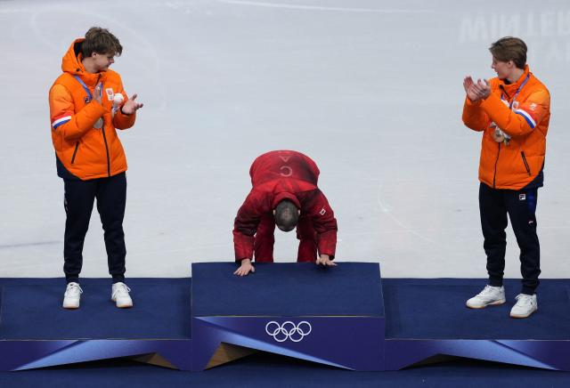(260219) -- MILAN, Feb. 19, 2026 (Xinhua) -- Gold medallist Steven Dubois (C) of Canada touches the podium during the awarding ceremony for the short track speed skating men's 500m final A at the Milan-Cortina 2026 Olympic Winter Games in Milan, Italy, Feb. 18, 2026. (Xinhua/Xue Yuge)