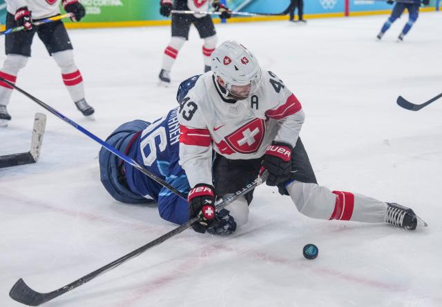 (260219) -- MILAN, Feb. 19, 2026 (Xinhua) -- Andrea Glauser (R) of Switzerland vies for the puck during the ice hockey men's play-offs quarterfinal between Finland and Switzerland at the Milan-Cortina 2026 Olympic Winter Games in Milan, Italy, Feb. 18, 2026. (Xinhua/Sun Fei)