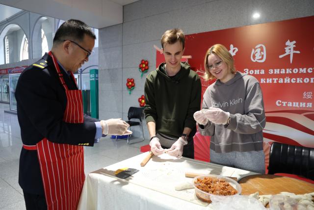 (260219) -- BEIJING, Feb. 19, 2026 (Xinhua) -- Foreign tourists experience making dumplings at the Suifenhe Railway Station in Suifenhe City, northeast China's Heilongjiang Province, Feb. 10, 2026. (Photo by Qu Yiwei/Xinhua)