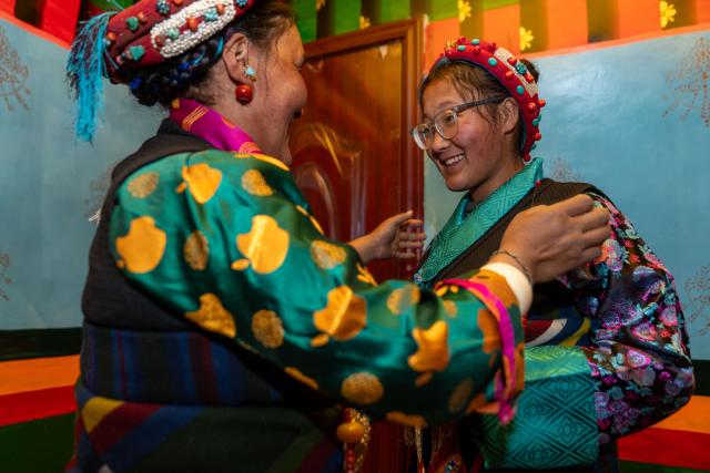 (260219) -- LHASA, Feb. 19, 2026 (Xinhua) -- Drolma Tsering (L) arranges clothes for her daughter Tenzin Wangmo at home in Gurum Village of Chamco Township, Dingri County, southwest China's Xizang Autonomous Region, Feb. 16, 2026.
  Monday was the Chinese New Year's Eve, which coincided with the Night of Gutu of the Tibetan calendar. Enjoying the festive atmosphere, the family of Sangs-rgyas purchased new furniture and stocked up on New Year goods, celebrating their first Spring Festival and Tibetan New Year after moving into their new house.
  Last year, a 6.8 magnitude earthquake hit Dingri, home to the northern base camp of the world's highest peak, Mount Qomolangma, and other counties in the region on Jan. 7. In less than three days after the earthquake, Xizang rolled out a post-disaster reconstruction plan and kicked off the reconstruction work later. In the second half of 2025, the family of Sangs-rgyas moved into a safe and comfortable new residence. (Xinhua/Tenzing Nima Qadhup)
