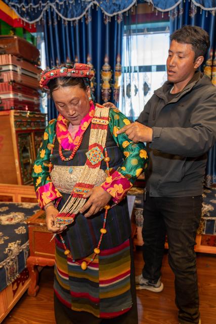 (260219) -- LHASA, Feb. 19, 2026 (Xinhua) -- Sangs-rgyas (R) helps his wife Drolma Tsering wear accessories at home in Gurum Village of Chamco Township, Dingri County, southwest China's Xizang Autonomous Region, Feb. 16, 2026.
  Monday was the Chinese New Year's Eve, which coincided with the Night of Gutu of the Tibetan calendar. Enjoying the festive atmosphere, the family of Sangs-rgyas purchased new furniture and stocked up on New Year goods, celebrating their first Spring Festival and Tibetan New Year after moving into their new house.
  Last year, a 6.8 magnitude earthquake hit Dingri, home to the northern base camp of the world's highest peak, Mount Qomolangma, and other counties in the region on Jan. 7. In less than three days after the earthquake, Xizang rolled out a post-disaster reconstruction plan and kicked off the reconstruction work later. In the second half of 2025, the family of Sangs-rgyas moved into a safe and comfortable new residence. (Xinhua/Tenzing Nima Qadhup)