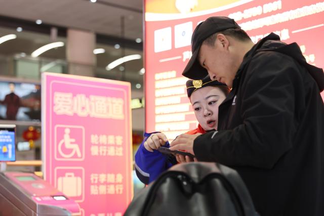 (260219) -- BEIJING, Feb. 19, 2026 (Xinhua) -- A staff member (L) helps a passenger at the metro station of Tianjin West Railway Station in north China's Tianjin, Feb. 19, 2026. During the Spring Festival travel season, civil aviation, railway, and other departments have increased transportation capacity and optimized convenient services such as air-rail intermodal transport, quiet carriages, luggage delivery, and priority channels for vulnerable groups, taking multiple measures to ensure passengers' safe and smooth travel. (Xinhua/Li Ran)