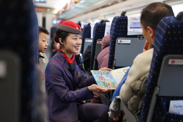 (260219) -- BEIJING, Feb. 19, 2026 (Xinhua) -- A staff member comforts a child inside a quiet carriage of train D2719 travelling from Xi'an of northwest China's Shaanxi Province to Wuwei of northwest China's Gansu Province, Feb. 18, 2026. During the Spring Festival travel season, civil aviation, railway, and other departments have increased transportation capacity and optimized convenient services such as air-rail intermodal transport, quiet carriages, luggage delivery, and priority channels for vulnerable groups, taking multiple measures to ensure passengers' safe and smooth travel. (Photo by Liu Xiang/Xinhua)