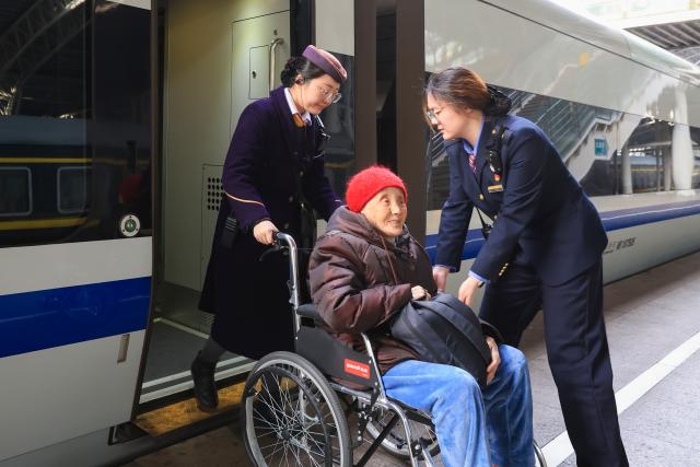 (260219) -- BEIJING, Feb. 19, 2026 (Xinhua) -- Staff members help an elderly passenger board a train at Nanjing Railway Station in Nanjing City, east China's Jiangsu Province, Feb. 19, 2026. During the Spring Festival travel season, civil aviation, railway, and other departments have increased transportation capacity and optimized convenient services such as air-rail intermodal transport, quiet carriages, luggage delivery, and priority channels for vulnerable groups, taking multiple measures to ensure passengers' safe and smooth travel. (Photo by Su Yang/Xinhua)