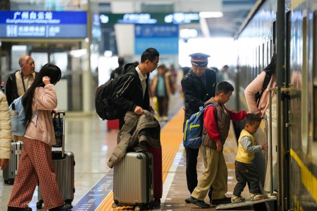 (260219) -- BEIJING, Feb. 19, 2026 (Xinhua) -- A staff member helps passengers board a train at Guangzhou Baiyun Railway Station in Guangzhou, south China's Guangdong Province, Feb. 19, 2026. During the Spring Festival travel season, civil aviation, railway, and other departments have increased transportation capacity and optimized convenient services such as air-rail intermodal transport, quiet carriages, luggage delivery, and priority channels for vulnerable groups, taking multiple measures to ensure passengers' safe and smooth travel. (Xinhua/Wu Lu)