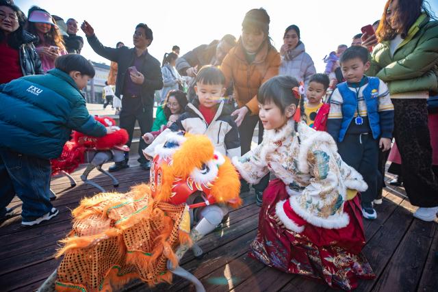 (260219) -- BEIJING, Feb. 19, 2026 (Xinhua) -- A child interacts with a robot dog at a wetland park in Xinghua City, east China's Jiangsu Province, Feb. 19, 2026. During the Spring Festival, various folk activities and performances are held across China. (Photo by Zhou Shegen/Xinhua)