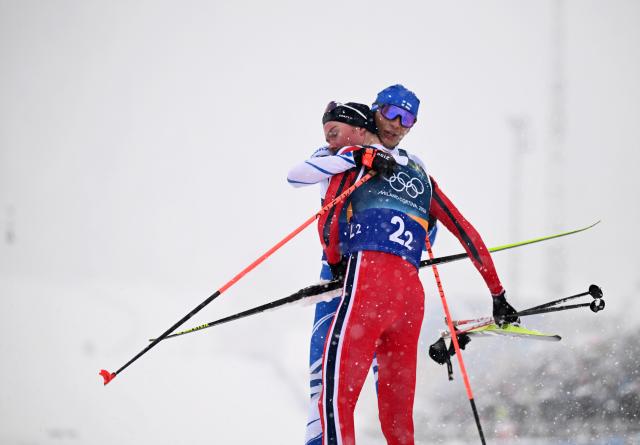 (260219) -- TESERO, Feb. 19, 2026 (Xinhua) -- Jens Luraas Oftebro (front) of Norway hugs Eero Hirvonen of Finland after the cross-country event of the nordic combined team sprint at the 2026 Milan-Cortina Winter Olympics in Tesero, Italy, Feb. 19, 2026. (Xinhua/He Canling)