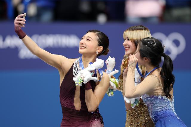 (260219) -- MILAN, Feb. 19, 2026 (Xinhua) -- Gold medalist Alysa Liu (C) of the United States, silver medalist Sakamoto Kaori (L) of Japan and bronze medalist Nakai Ami of Japan take a selfie during the awarding ceremony of the figure skating women single skating event at the Milan-Cortina 2026 Olympic Winter Games in Milan, Italy, Feb. 19, 2026. (Xinhua/Li Ming)