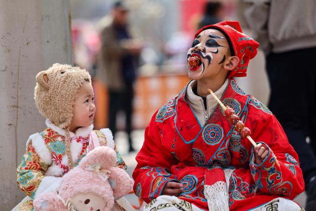 (260220) -- BEIJING, Feb. 20, 2026 (Xinhua) -- A child interacts with a performer at a folk culture show in Lanzhou, northwest China's Gansu Province, Feb. 18, 2026. During the Spring Festival, various folk activities and performances are held across China. (Photo by Hou Chonghui/Xinhua)
