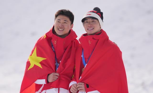 (260220) -- LIVIGNO, Feb. 20, 2026 (Xinhua) -- Gold medalist Wang Xindi of China and his teammate Li Tianma pose during the awarding ceremony of the freestyle skiing men's aerials at the Milan-Cortina 2026 Olympic Winter Games in Livigno, Italy, Feb. 20, 2026. (Xinhua/Hu Chao)