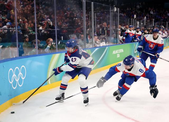 (260221) -- MILAN, Feb. 21, 2026 (Xinhua) -- Quinn Hughes (L) of the United States and Oliver Okuliar (C) of Slovakia battle for the puck during the ice hockey men's play-offs semifinal match between the United States and Slovakia at the Milan-Cortina 2026 Olympic Winter Games in Milan, Italy, Feb. 20, 2026. (Xinhua/Wang Kaiyan)