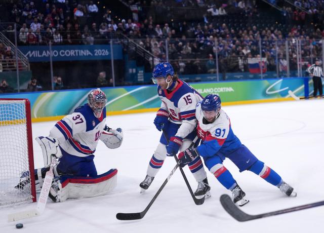 (260221) -- MILAN, Feb. 21, 2026 (Xinhua) -- Matus Sukel (R) of Slovakia and Noah Hanifin (C) of the United States battle for the puck during the ice hockey men's play-offs semifinal match between the United States and Slovakia at the Milan-Cortina 2026 Olympic Winter Games in Milan, Italy, Feb. 20, 2026. (Xinhua/Tao Xiyi)