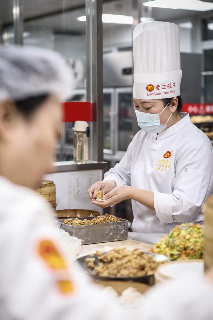 (260221) -- SHENYANG, Feb. 21, 2026 (Xinhua) -- Zheng Chunxiang, the fifth-generation inheritor of traditional dumpling-making techniques at Laobian Dumplings, makes dumplings in Shenyang, northeast China's Liaoning Province, Feb. 21, 2026. On the fifth day of the Chinese lunar new year, also known as "Powu," a dumpling-eating tradition is observed in many regions across China to ward off evil and disaster, embrace good fortune, and express hopes for the new year. (Xinhua/Pan Yulong)