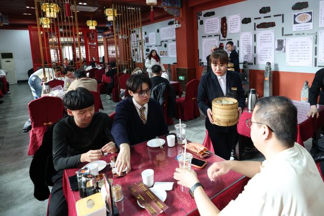 (260221) -- SHENYANG, Feb. 21, 2026 (Xinhua) -- A staff member serves dumplings at Laobian Dumplings, a restaurant chain, in Shenyang, northeast China's Liaoning Province, Feb. 21, 2026. On the fifth day of the Chinese lunar new year, also known as "Powu," a dumpling-eating tradition is observed in many regions across China to ward off evil and disaster, embrace good fortune, and express hopes for the new year. (Xinhua/Pan Yulong)