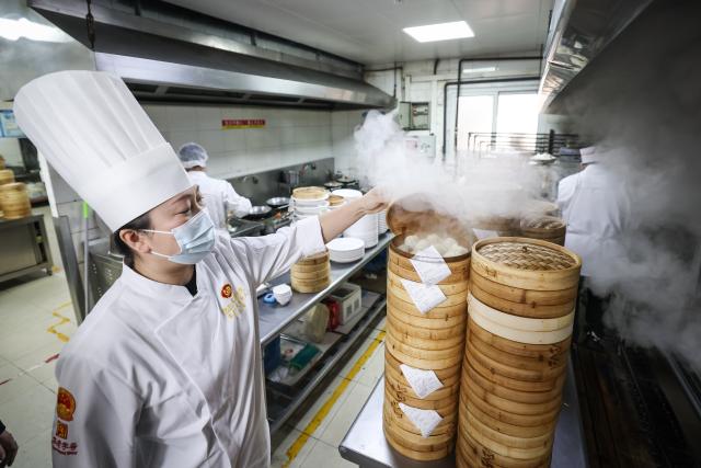 (260221) -- SHENYANG, Feb. 21, 2026 (Xinhua) -- Zheng Chunxiang, the fifth-generation inheritor of traditional dumpling-making techniques at Laobian Dumplings, checks on steamed dumplings in Shenyang, northeast China's Liaoning Province, Feb. 21, 2026. On the fifth day of the Chinese lunar new year, also known as "Powu," a dumpling-eating tradition is observed in many regions across China to ward off evil and disaster, embrace good fortune, and express hopes for the new year. (Xinhua/Pan Yulong)