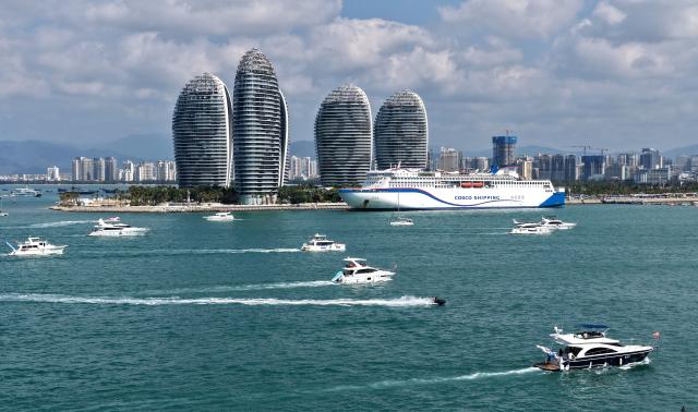 (260221) -- SANYA, Feb. 21, 2026 (Xinhua) -- A drone photo taken on Feb. 21, 2026 shows tourists taking yachts in Sanya, south China's Hainan Province. During the first Spring Festival holiday since the launch of island-wide special customs operations in China's Hainan Free Trade Port (FTP), the southern tropical island has become a popular destination for yachting. According to data, over 7,000 yacht voyages were made in Sanya in the first six days of the Spring Festival holiday. (Xinhua/Zhao Yingquan)