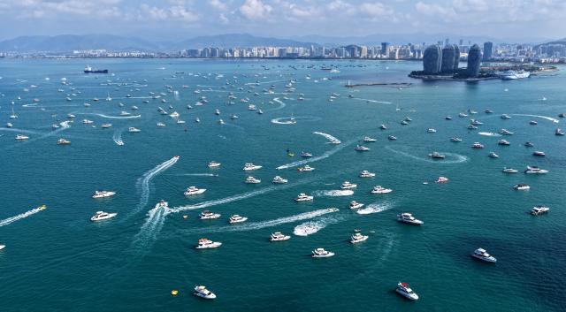 (260221) -- SANYA, Feb. 21, 2026 (Xinhua) -- A drone photo taken on Feb. 21, 2026 shows tourists taking yachts in Sanya, south China's Hainan Province. During the first Spring Festival holiday since the launch of island-wide special customs operations in China's Hainan Free Trade Port (FTP), the southern tropical island has become a popular destination for yachting. According to data, over 7,000 yacht voyages were made in Sanya in the first six days of the Spring Festival holiday. (Xinhua/Zhao Yingquan)