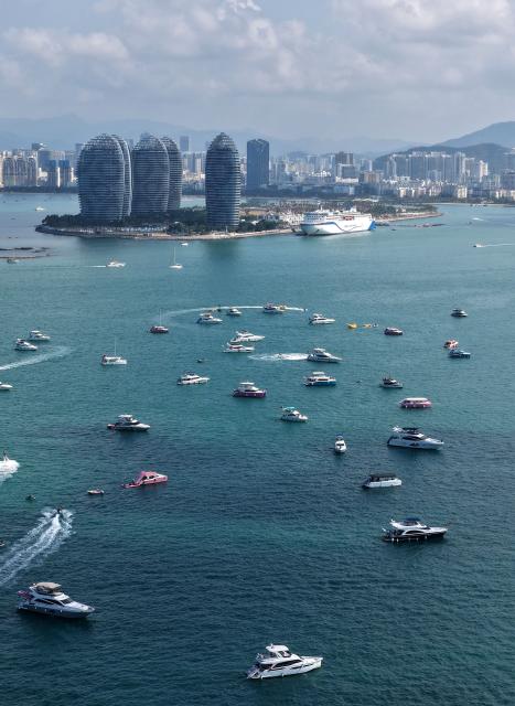 (260221) -- SANYA, Feb. 21, 2026 (Xinhua) -- A drone photo taken on Feb. 21, 2026 shows tourists taking yachts in Sanya, south China's Hainan Province. During the first Spring Festival holiday since the launch of island-wide special customs operations in China's Hainan Free Trade Port (FTP), the southern tropical island has become a popular destination for yachting. According to data, over 7,000 yacht voyages were made in Sanya in the first six days of the Spring Festival holiday. (Xinhua/Zhao Yingquan)