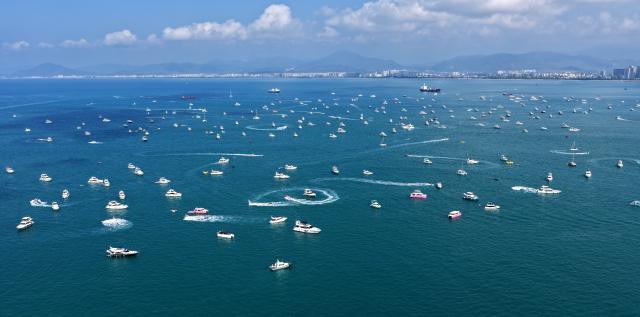 (260221) -- SANYA, Feb. 21, 2026 (Xinhua) -- A drone photo taken on Feb. 21, 2026 shows tourists taking yachts in Sanya, south China's Hainan Province. During the first Spring Festival holiday since the launch of island-wide special customs operations in China's Hainan Free Trade Port (FTP), the southern tropical island has become a popular destination for yachting. According to data, over 7,000 yacht voyages were made in Sanya in the first six days of the Spring Festival holiday. (Xinhua/Zhao Yingquan)