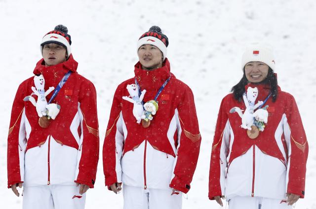 (260221) -- LIVIGNO, Feb. 21, 2026 (Xinhua) -- Bronze Medalists Li Tianma, Wang Xindi and Xu Mengtao (L to R) of China react during the awarding ceremony for freestyle skiing mixed team aerials at the Milan-Cortina 2026 Olympic Winter Games in Livigno, Italy, Feb. 21, 2026. (Xinhua/Wang Peng)