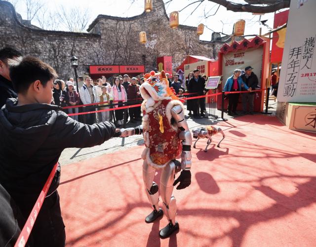 (260221) -- TONGXIANG, Feb. 21, 2026 (Xinhua) -- A tourist shakes hands with a robot in Wuzhen, Tongxiang City, east China's Zhejiang Province, Feb. 21, 2026. During this Spring Festival holiday, the ancient water town of Wuzhen launched over sixty activities which present the town's rich history and modern vitality reflected in folk customs, drama, science and technology, and culture. (Xinhua/Xu Yu)