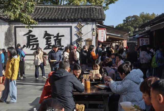 (260221) -- TONGXIANG, Feb. 21, 2026 (Xinhua) -- Tourists have breakfast at a morning market in Wuzhen, Tongxiang City, east China's Zhejiang Province, Feb. 21, 2026. During this Spring Festival holiday, the ancient water town of Wuzhen launched over sixty activities which present the town's rich history and modern vitality reflected in folk customs, drama, science and technology, and culture. (Xinhua/Xu Yu)