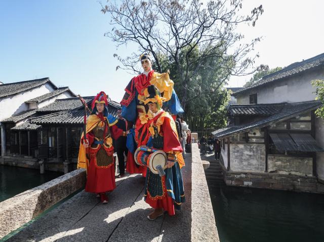 (260221) -- TONGXIANG, Feb. 21, 2026 (Xinhua) -- Artists perform during a parade in Wuzhen, Tongxiang City, east China's Zhejiang Province, Feb. 21, 2026. During this Spring Festival holiday, the ancient water town of Wuzhen launched over sixty activities which present the town's rich history and modern vitality reflected in folk customs, drama, science and technology, and culture. (Xinhua/Xu Yu)