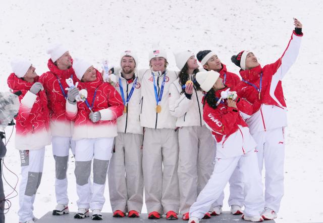 (260221) -- LIVIGNO, Feb. 21, 2026 (Xinhua) -- Bronze medalist Wang Xindi (1st R) of China takes selfies for atheltes at the awarding ceremony for freestyle skiing mixed team aerials at the Milan-Cortina 2026 Olympic Winter Games in Livigno, Italy, Feb. 21, 2026. (Xinhua/Hu Chao)