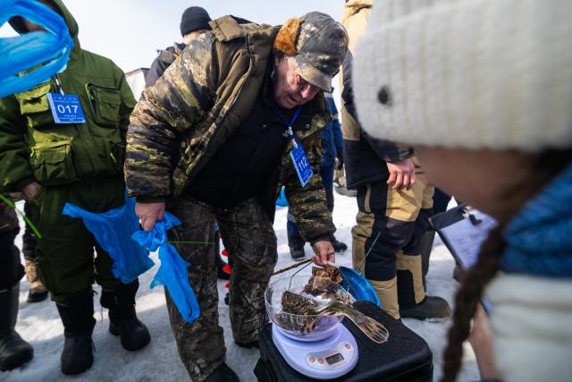 (260221) -- VLADIVOSTOK, Feb. 21, 2026 (Xinhua) -- A man participating in an ice fishing competition hands over his catches to the referees for weighing in Vladivostok, Russia, Feb. 21, 2026. (Photo by Andrey Matveenko/Xinhua)