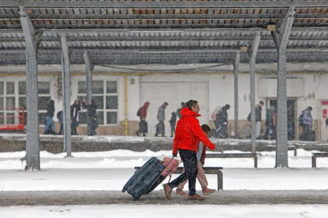 (260221) -- BUCHAREST, Feb. 21, 2026 (Xinhua) -- People carry their luggage amid snowfall on a platform at North Railway station in Bucharest, Romania, on Feb. 21, 2026. Heavy snow, strong winds and icy conditions on Saturday again affected roads, maritime ports and power supplies across southern and eastern Romania, according to authorities. (Photo by Cristian Cristel/Xinhua)
