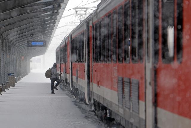 (260221) -- BUCHAREST, Feb. 21, 2026 (Xinhua) -- A passenger boards a train amid snowfall at North Railway station in Bucharest, Romania, on Feb. 21, 2026. Heavy snow, strong winds and icy conditions on Saturday again affected roads, maritime ports and power supplies across southern and eastern Romania, according to authorities. (Photo by Cristian Cristel/Xinhua)