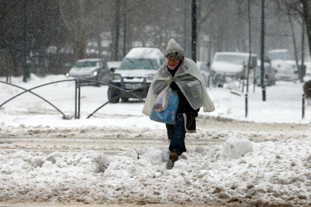 (260221) -- BUCHAREST, Feb. 21, 2026 (Xinhua) -- A woman walks amid snowfall on a snow-covered street in Bucharest, Romania, on Feb. 21, 2026. Heavy snow, strong winds and icy conditions on Saturday again affected roads, maritime ports and power supplies across southern and eastern Romania, according to authorities. (Photo by Cristian Cristel/Xinhua)