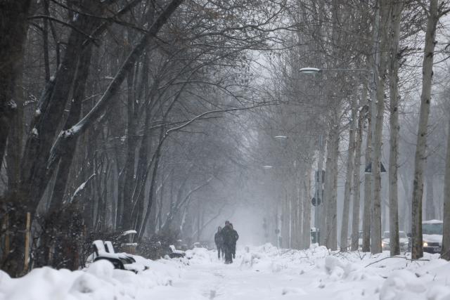 (260221) -- BUCHAREST, Feb. 21, 2026 (Xinhua) -- People walk amid snowfall on a snow-covered alley in Bucharest, Romania, on Feb. 21, 2026. Heavy snow, strong winds and icy conditions on Saturday again affected roads, maritime ports and power supplies across southern and eastern Romania, according to authorities. (Photo by Cristian Cristel/Xinhua)