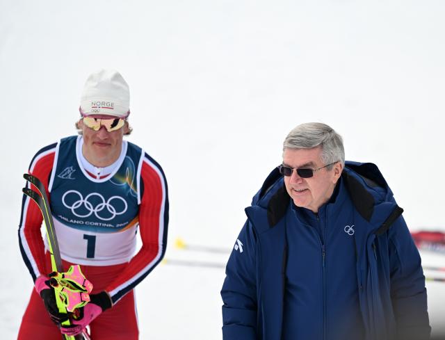 (260221) -- TESERO, Feb. 21, 2026 (Xinhua) -- Gold medalist Johannes Hoesflot Klaebo (L) of Norway reacts with International Olympic Committee Honorary President Thomas Bach after the cross-country skiing men's 50km mass start classic event at the Milan-Cortina 2026 Olympic Winter Games in Tesero, Italy, Feb. 21, 2026. (Xinhua/He Canling)