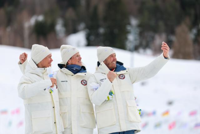 (260221) -- TESERO, Feb. 21, 2026 (Xinhua) -- Gold medalist Johannes Hoesflot Klaebo (C) of Norway, silver medalist Martin Loewstroem Nyenget (L) of Norway and bronze medalist Emil Iversen of Norway take selfies on the podium after the cross-country skiing men's 50km mass start classic event at the Milan-Cortina 2026 Olympic Winter Games in Tesero, Italy, Feb. 21, 2026. (Xinhua/Huang Wei)