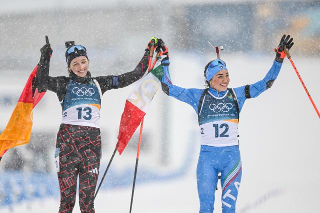 (260221) -- ANTERSELVA, Feb. 21, 2026 (Xinhua) -- Franziska Preuss (L) of Germany and Dorothea Wierer of Italy wave after the biathlon women's 12.5km mass start event at the 2026 Milan-Cortina Winter Olympics in Anterselva, Italy, Feb. 21, 2026. (Xinhua/Jiang Han)