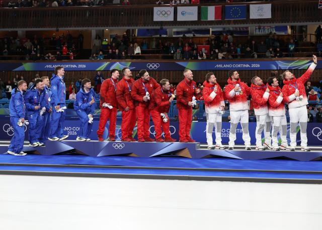 (260222) -- CORTINA D'AMPEZZO, Feb. 22, 2026 (Xinhua) -- Gold medalists team Canada (C), silver medalists team Britain (L) and bronze medalists team Switzerland pose for selfies during the awarding ceremony after the curling men's gold medal game between Canada and Britain at the 2026 Milan-Cortina Winter Olympics in Cortina, Italy, Feb. 21, 2026. (Xinhua/Zhang Chenlin)
