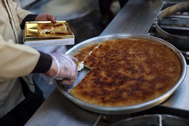 (260222) -- CAIRO, Feb. 22, 2026 (Xinhua) -- A baker slices traditional sweets known as "Kunafa" for sale during the holy month of Ramadan in Cairo, Egypt, on Feb. 21, 2026. Egyptians eat traditional sweets during Ramadan to break their fast. (Xinhua/Ahmed Gomaa)