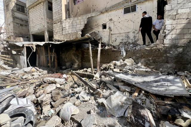 (260222) -- SIDON, Feb. 22, 2026 (Xinhua) -- Palestinians stand in front of the destruction caused by an Israeli airstrike on a neighborhood inside the Ain al-Hilweh Palestinian refugee camp in the city of Sidon, southern Lebanon, Feb. 21, 2026. Two people were killed, and several others were injured on Friday in an Israeli airstrike on a neighborhood inside the Ain al-Hilweh Palestinian refugee camp in the city of Sidon in southern Lebanon, local public health authorities and media reported. (Photo by Ali Hashisho/Xinhua)