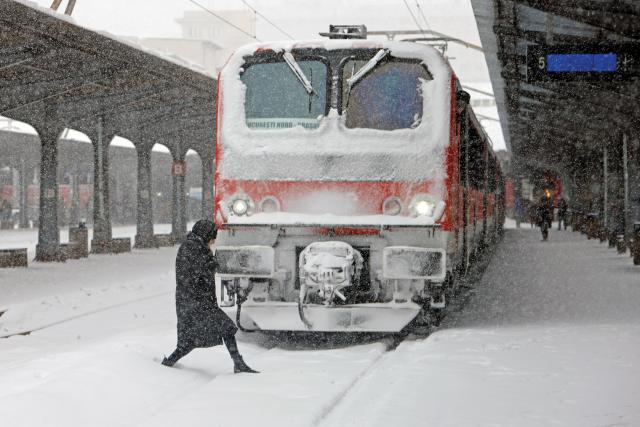 (260222) -- BEIJING, Feb. 22, 2026 (Xinhua) -- A woman walks amid snowfall in front of a train at North Railway station in Bucharest, Romania, on Feb. 21, 2026. (Photo by Cristian Cristel/Xinhua)