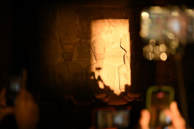 (260222) -- ASWAN, Feb. 22, 2026 (Xinhua) -- Tourists take photos at the Great Temple of Abu Simbel during the Sun Festival in Aswan, Egypt, Feb. 22, 2026. During the Sun Festival, which falls on Feb. 22 and Oct. 22 every year, rays of the morning sun would reach the innermost shrine of the Great Temple of Abu Simbel and illuminate the inside sculptures. (Xinhua/Xin Mengchen)