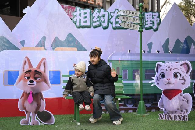 (260222) -- XINING, Feb. 22, 2026 (Xinhua) -- Children pose for photos in front of an installation at Xining Wildlife Park in northwest China's Qinghai Province, Feb. 22, 2026. Visitors came to Xining Wildlife Park to observe highland species including snow leopard during the Spring Festival holiday. (Xinhua/Zhang Long)