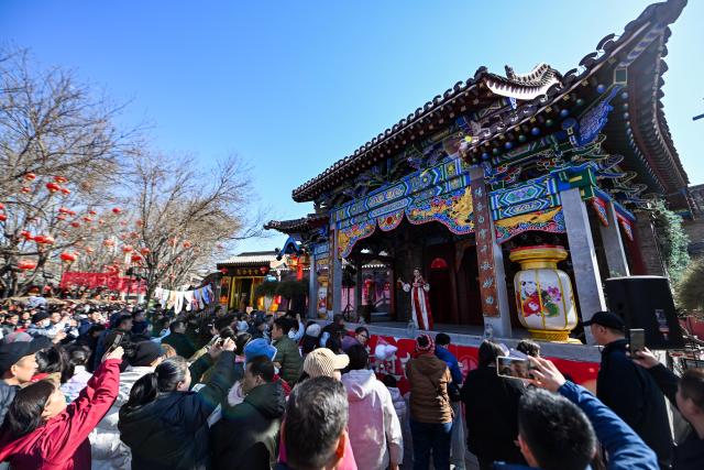 (260222) -- TIANJIN, Feb. 22, 2026 (Xinhua) -- Visitors watch a show at Yangliuqing ancient town in Tianjin, north China, Feb. 22, 2026. Yangliuqing ancient town launched a range of activities featuring folk customs, traditional culture and interactive experiences, offering visitors an immersive folk feast during this Spring Festival holiday. (Xinhua/Zhao Zishuo)