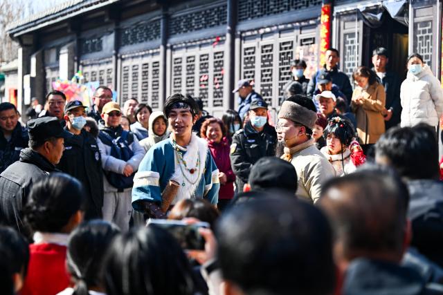 (260222) -- TIANJIN, Feb. 22, 2026 (Xinhua) -- Visitors watch a show at Yangliuqing ancient town in Tianjin, north China, Feb. 22, 2026. Yangliuqing ancient town launched a range of activities featuring folk customs, traditional culture and interactive experiences, offering visitors an immersive folk feast during this Spring Festival holiday. (Xinhua/Zhao Zishuo)