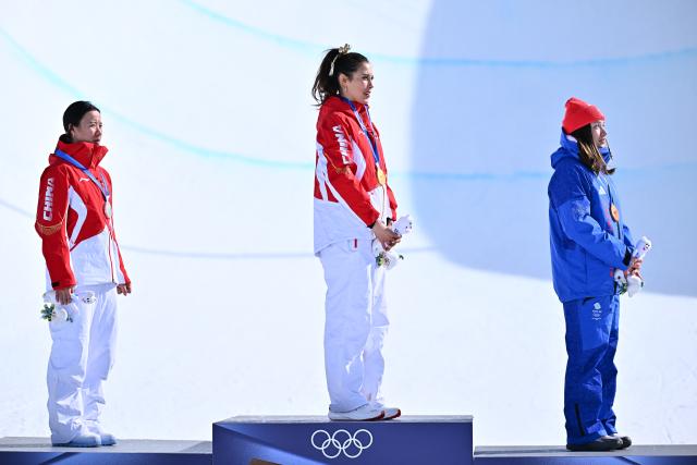 (260222) -- LIVIGNO, Feb. 22, 2026 (Xinhua) -- Silver medalist Li Fanghui (L) of China, gold medalist Gu Ailing (C) of China and bronze medalist Zoe Atkin of Britain react during the awarding ceremony for freestyle skiing women's freeski halfpipe at the Milan-Cortina 2026 Olympic Winter Games in Livigno, Italy, Feb. 22, 2026. (Xinhua/Zhang Hongxiang)