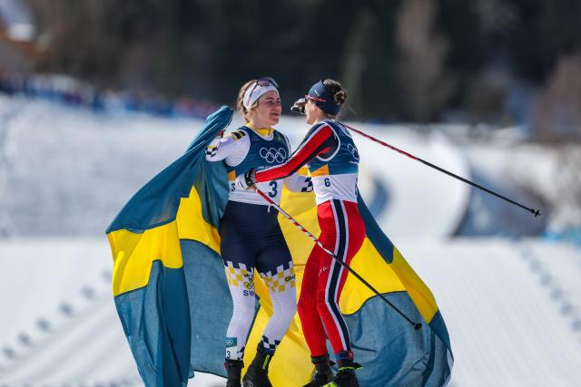 (260222) -- TESERO, Feb. 22, 2026 (Xinhua) -- Ebba Andersson (L) of Sweden hugs Heidi Weng of Norway after they finish the cross-country skiing women's 50km mass start classic match at the Milan-Cortina 2026 Olympic Winter Games in Tesero, Italy, Feb. 22, 2026. (Xinhua/Huang Wei)